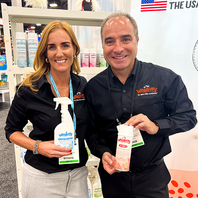 Adam and Emma, founders of WeeAway® in front of a WeeAway® display at a trade show.
